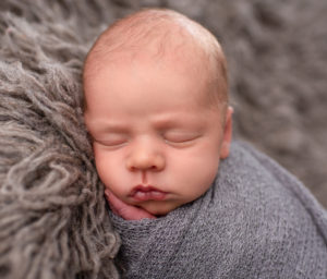 This is a newborn photography image of newborn Baby wrapped on grey blanket