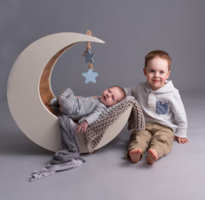 Newborn Baby on moon prop with big brother and grey seamless backdrop