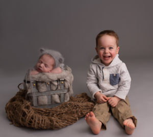 Newborn Baby in grey prop with big brother