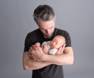 This is a newborn photography image of a Father with baby boy in newborn studio