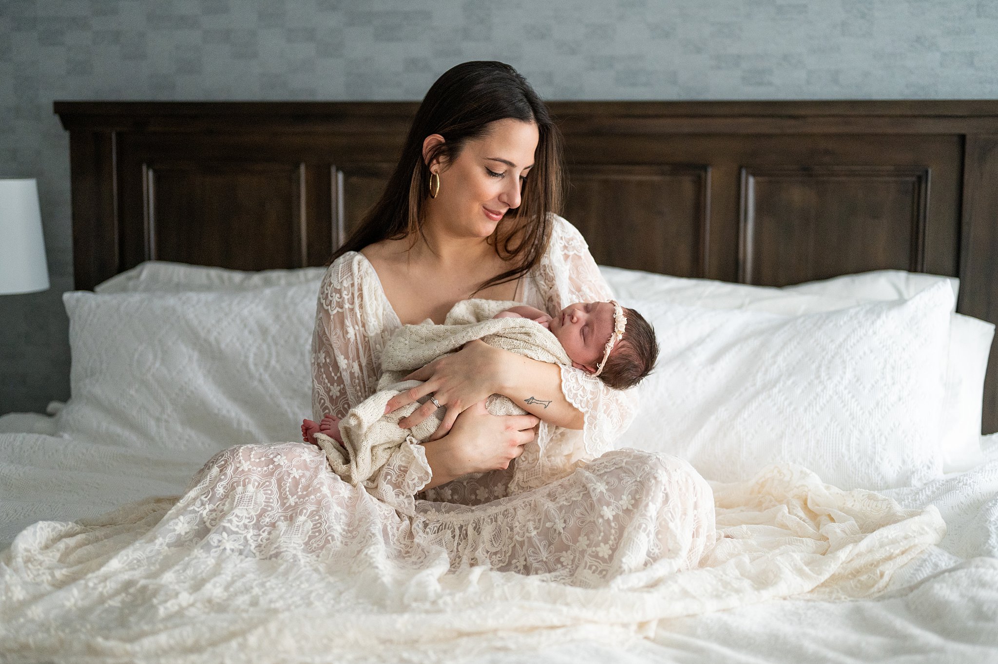 new mom in white gown from Ottawa Maternity Stores holding her newborn in bed