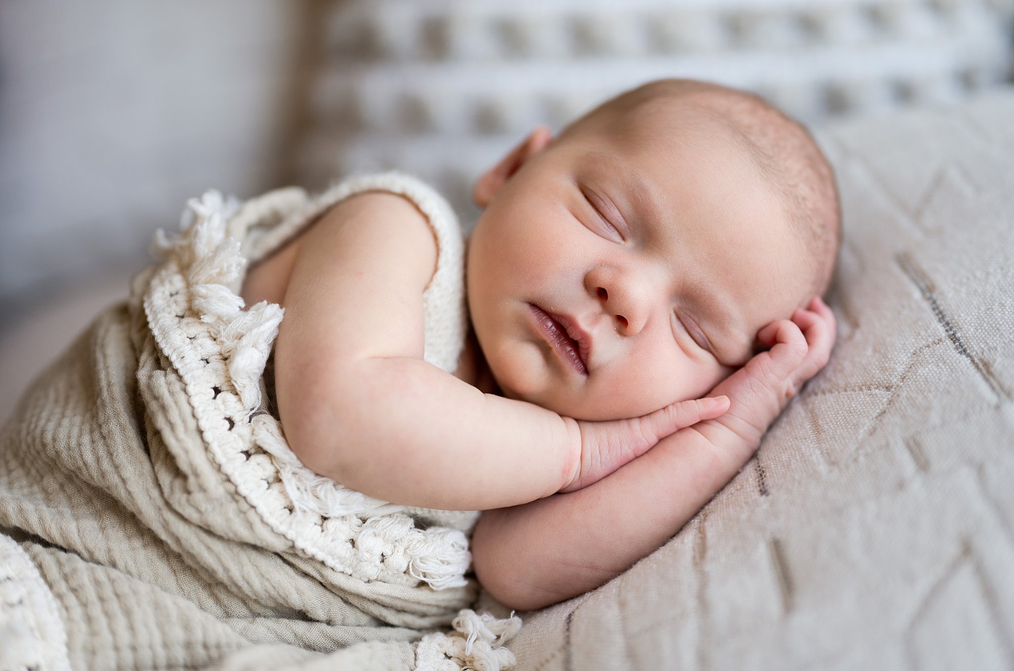 Newborn in knit overalls sleeps on their hands on a pillow baby stores in ottawa